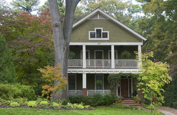 Sage-green two-story custom home with a double front porch and shade tree