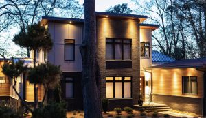 Modern two-story custom home exterior with wood and stone, lit at dusk