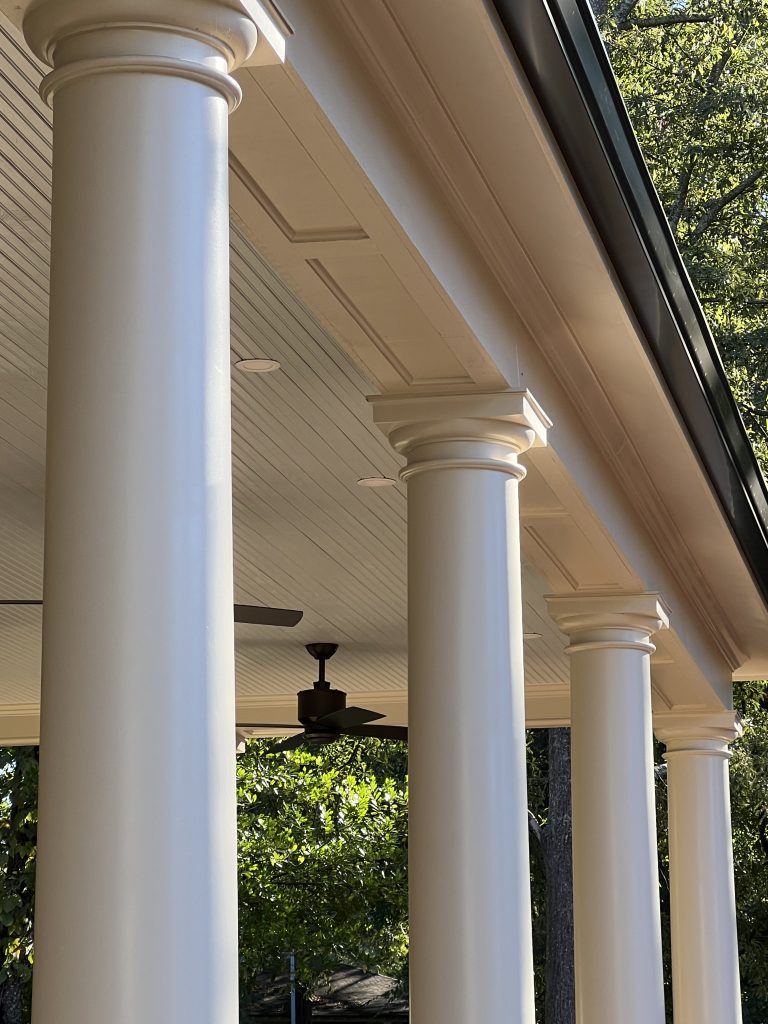 Covered front porch with white columns on a custom-built home exterior